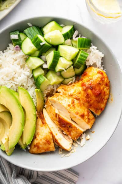 Bowl with harissa honey chicken, white rice, cucumber, and avocado.