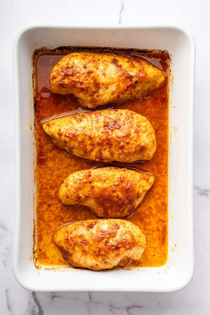 Baking dish with harissa honey chicken and sauce.