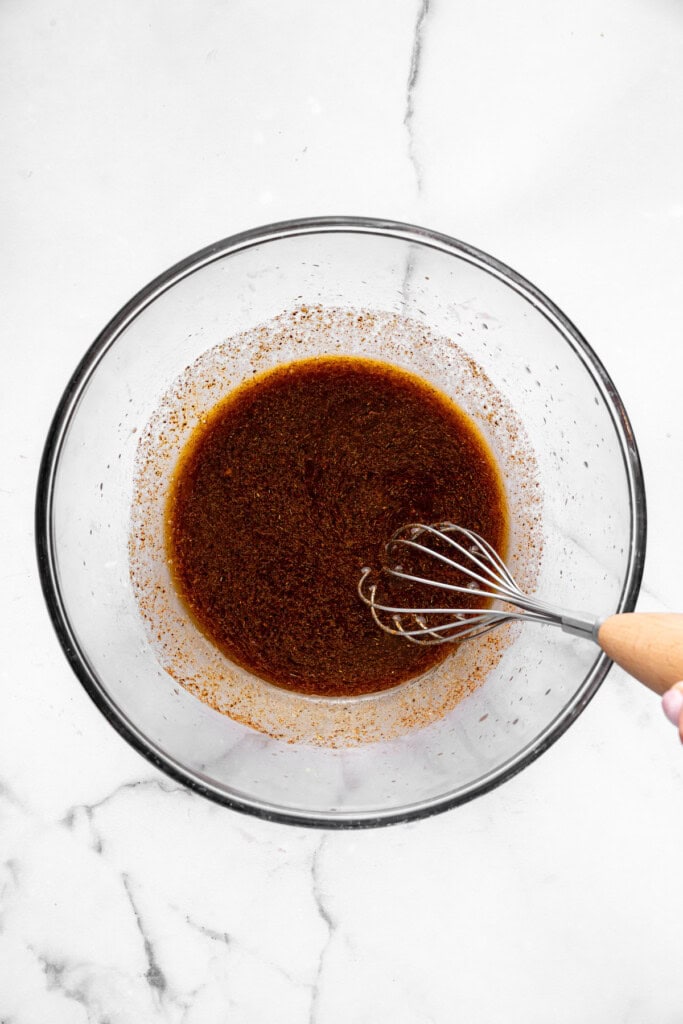 With black beans, crispy tofu and a sweet, tangy mango-peach salsa, these Air Fryer Tofu Tacos are the tastiest meatless dinner ever! Overhead view of marinade in bowl with whisk