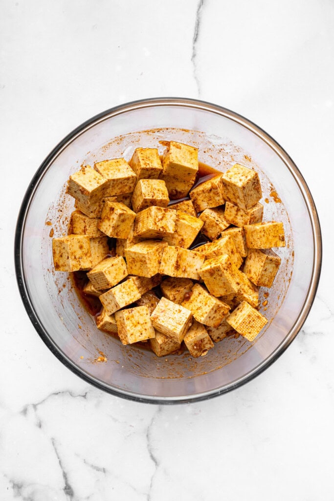 With black beans, crispy tofu and a sweet, tangy mango-peach salsa, these Air Fryer Tofu Tacos are the tastiest meatless dinner ever! Overhead view of tofu in bowl of marinade