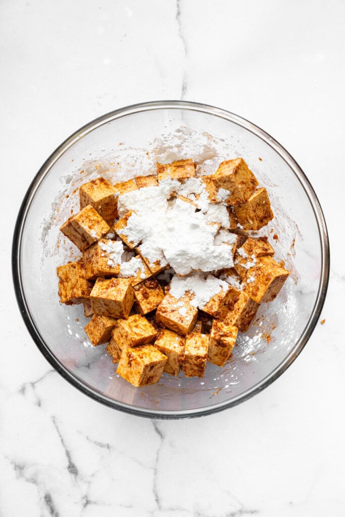 With black beans, crispy tofu and a sweet, tangy mango-peach salsa, these Air Fryer Tofu Tacos are the tastiest meatless dinner ever! Overhead view of cornstarch added to tofu in bowl