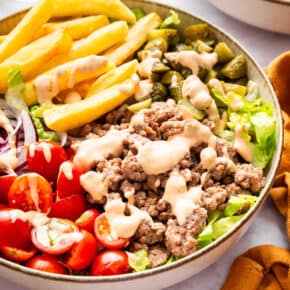 Burger bowl with fries, tomatoes, pickles, and special sauce.