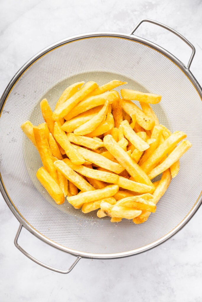 This Burger Bowl recipe gives you your burger fix, without the bun! It’s a fun protein-packed meal with crispy fries and your fave toppings. Fries in colander.