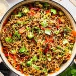 Pan of beef ramen with cilantro and green onions for garnish.