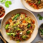 Two bowls of beef ramen and vegetables.