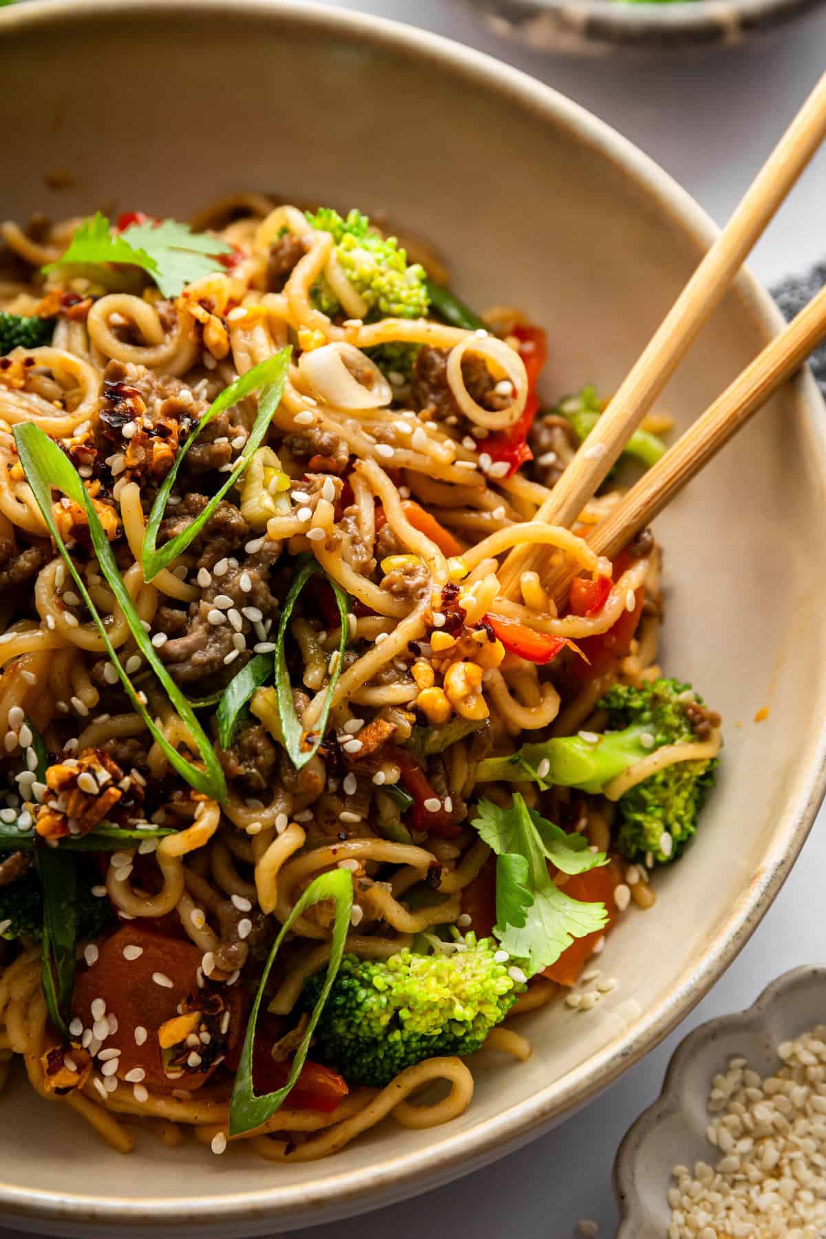 Springy ramen noodles are combined with ground beef and veggies to make this super easy one pan Beef Ramen recipe. Done in 25 minutes! Chopsticks in bowl of beef ramen with vegetables.