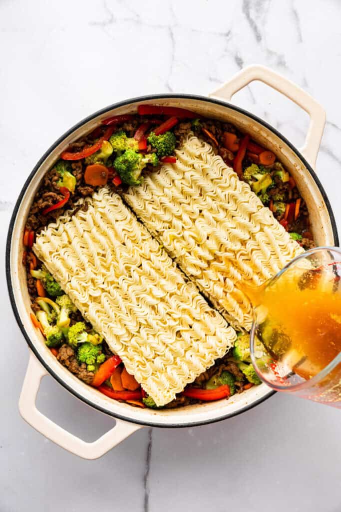 Springy ramen noodles are combined with ground beef and veggies to make this super easy one pan Beef Ramen recipe. Done in 25 minutes! Ramen and broth added to pan of veggies and ground beef.