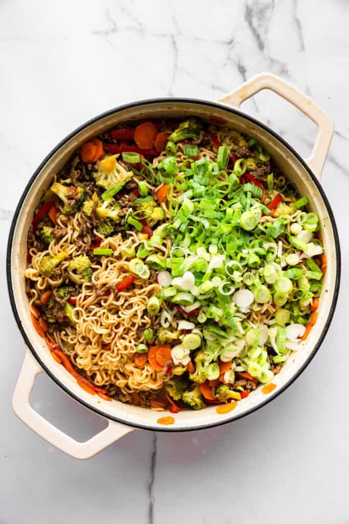 Springy ramen noodles are combined with ground beef and veggies to make this super easy one pan Beef Ramen recipe. Done in 25 minutes! Green onions added to pan of beef ramen.