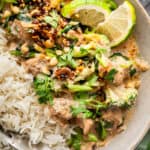 Salmon curry in bowl with rice and lime wedges.