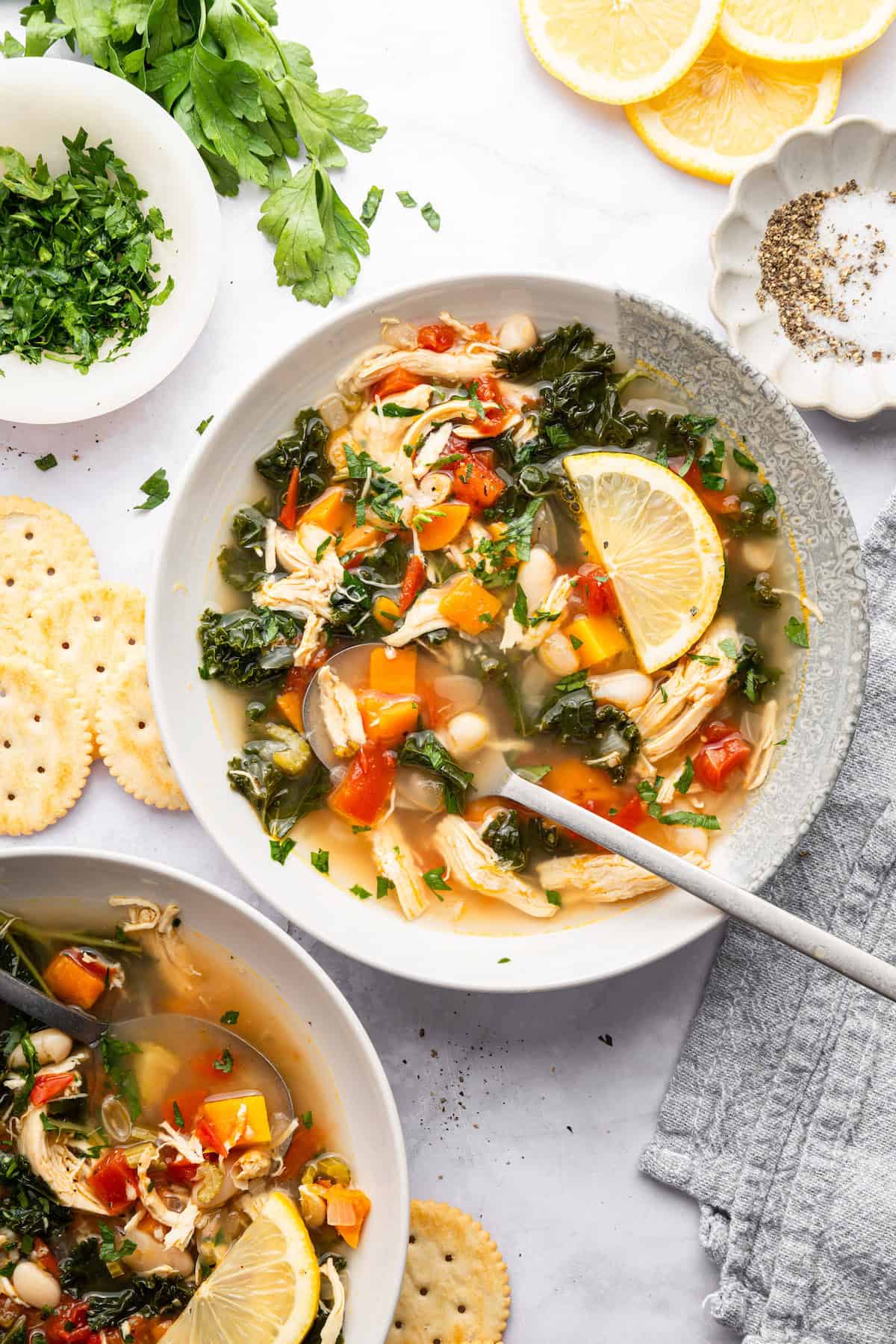 Bowls of chicken vegetable soup with lemon slices.