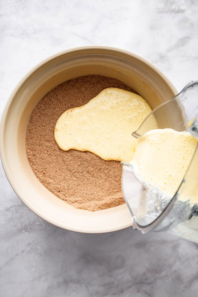 These easy Cottage Cheese Brownies are the perfect wholesome indulgence, with extra protein and whole grains in a rich, fudgy brownie! Pouring wet ingredients into bowl of dry ingredients for cottage cheese brownies.