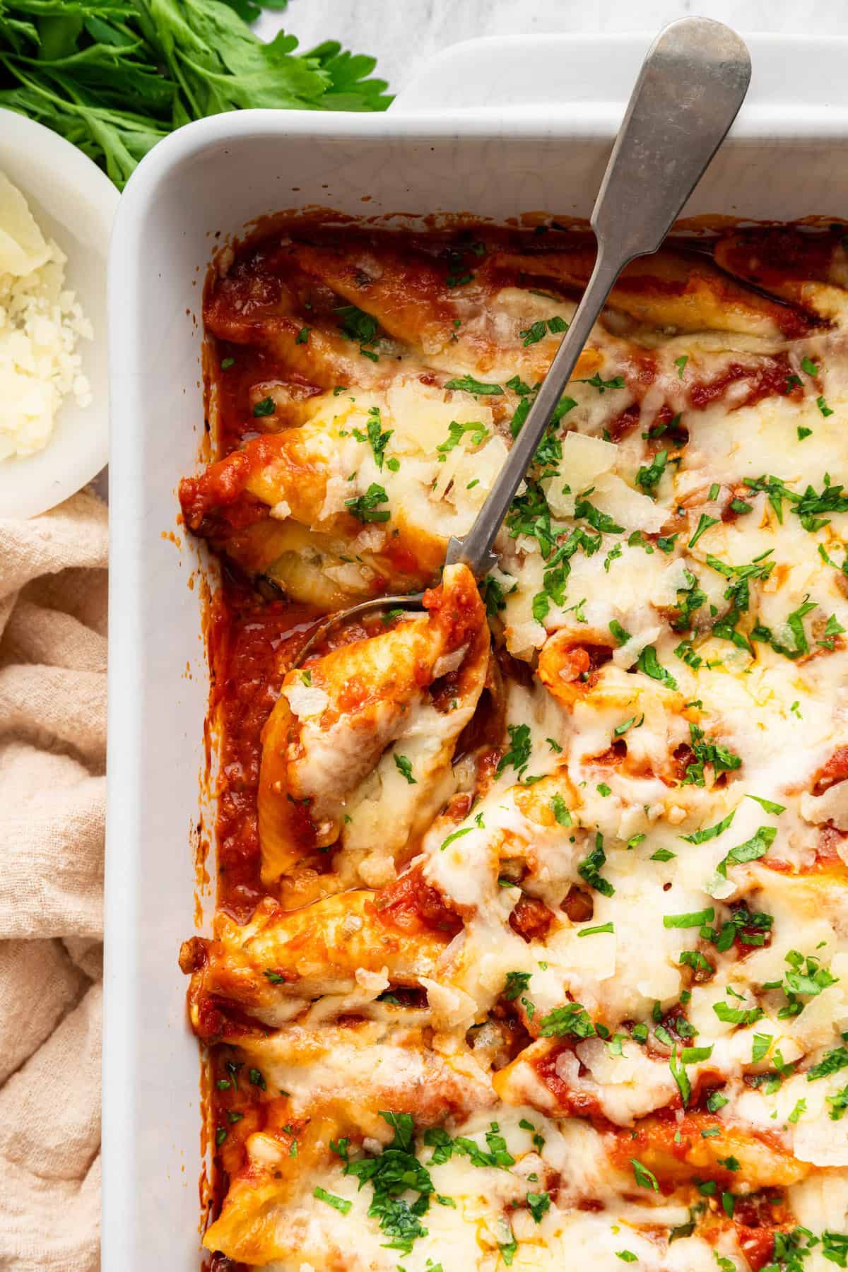 Spoon in casserole dish with stuffed shells.
