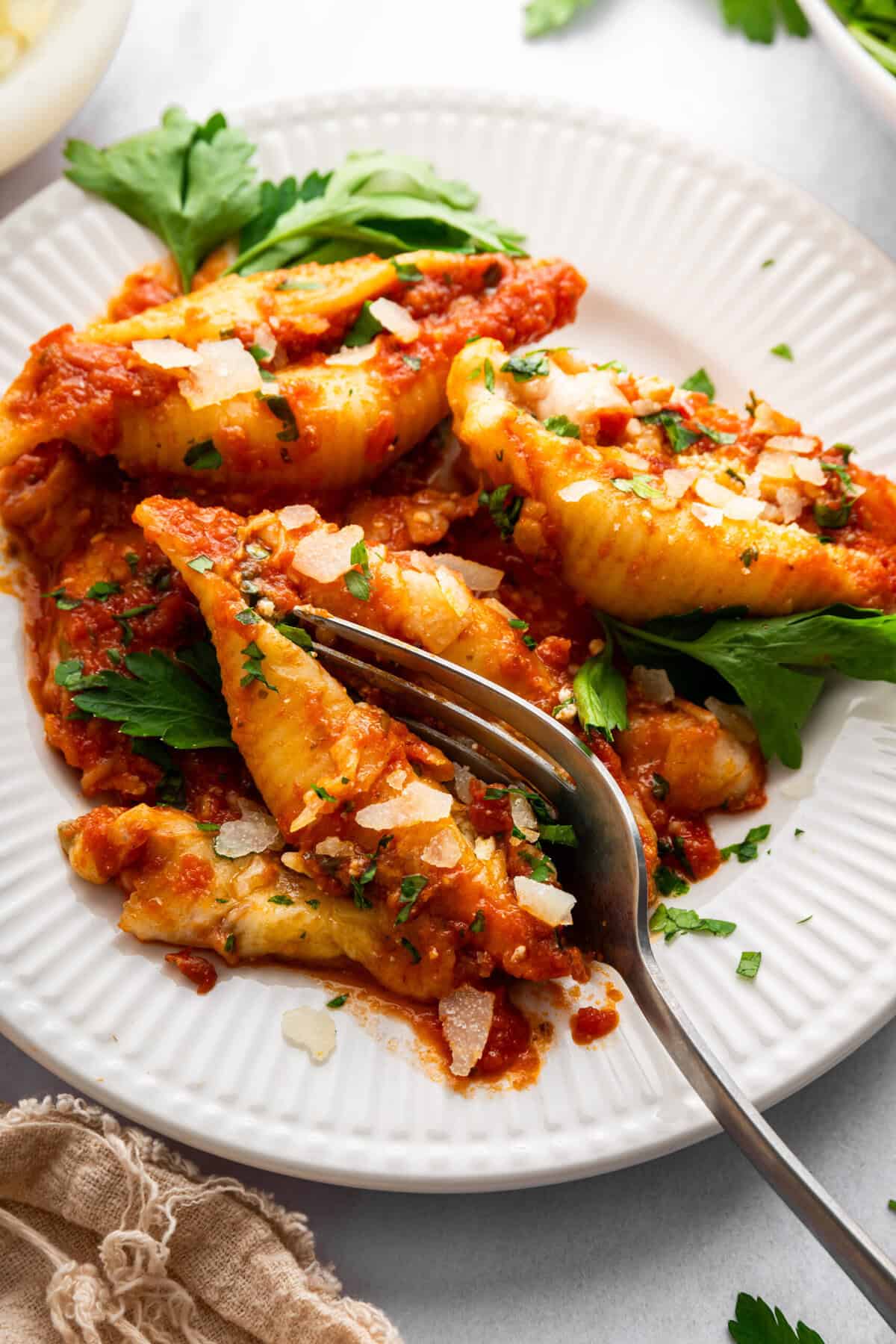 Fork cutting into stuffed shells on plate.