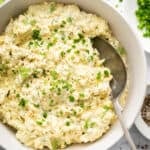 Egg salad in bowl with fresh herbs for garnish.