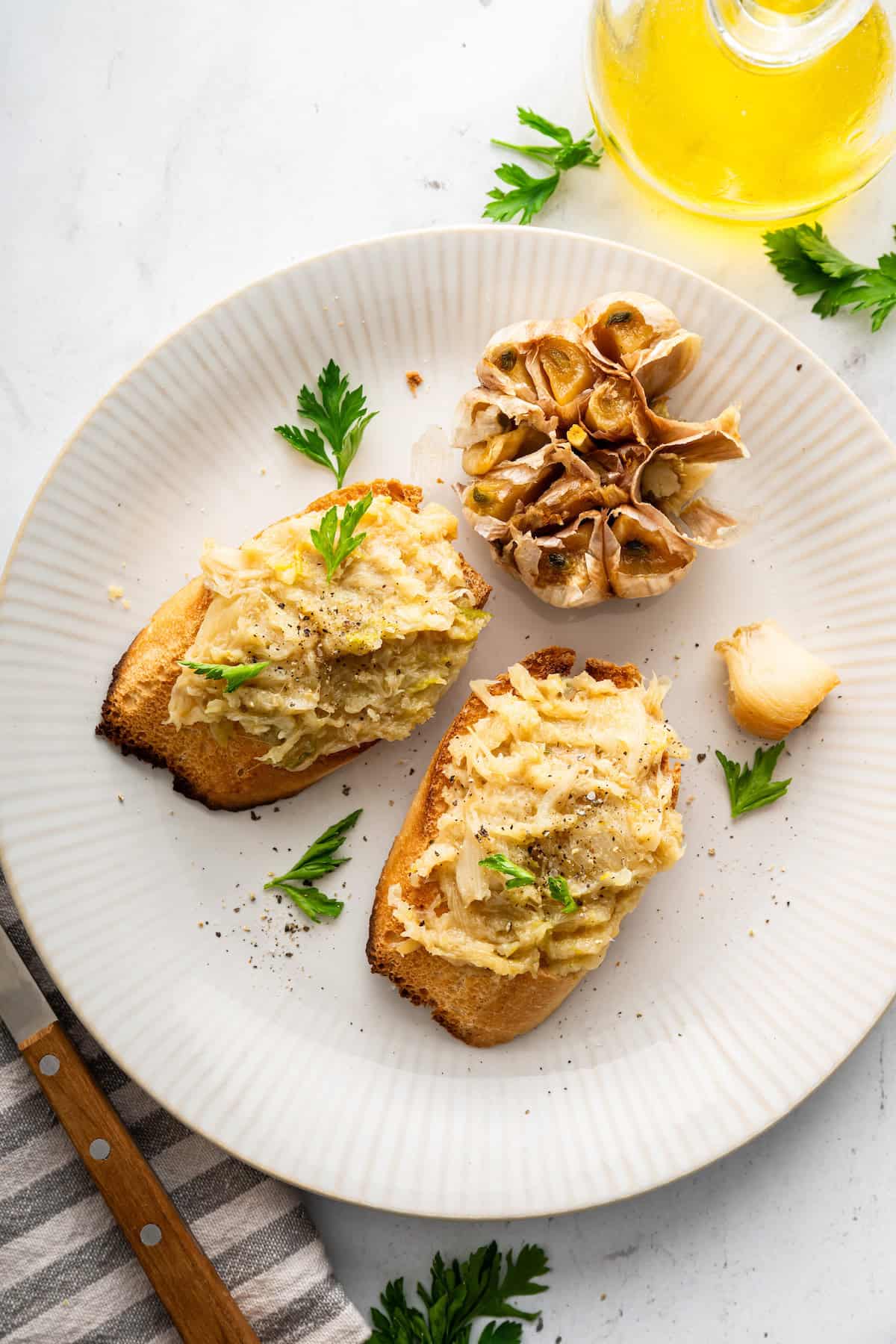 Two pieces of toast with roasted garlic on plate.