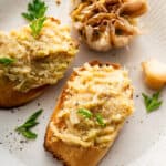 Two pieces of toast topped with oven roasted garlic.