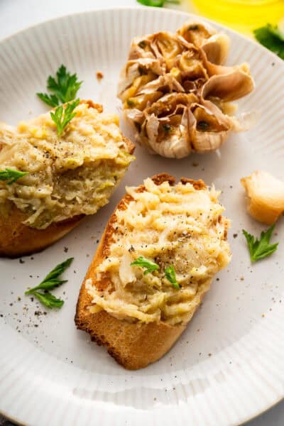 Two pieces of toast topped with oven roasted garlic.