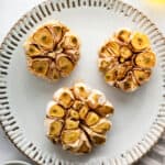Three bulbs of oven roasted garlic on plate.