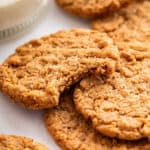 Pile of almond butter cookies with top cookie bitten into.