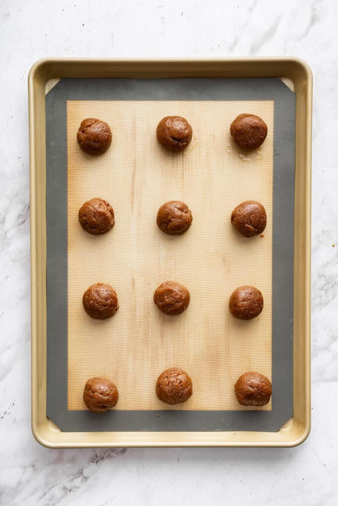 These easy almond butter cookies are made with just 5 ingredients! Naturally gluten-free, chewy with crisp edges, and full of nutty flavor. Balls of almond butter cookie dough on baking sheet.