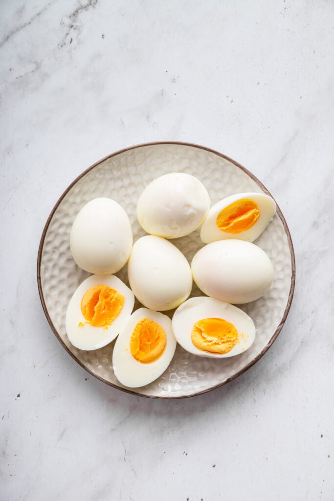 This creamy cottage cheese egg salad is a lighter version of the classic made without mayo. Higher in protein and perfect for meal prep! Hard boiled eggs on plate with some sliced in half.