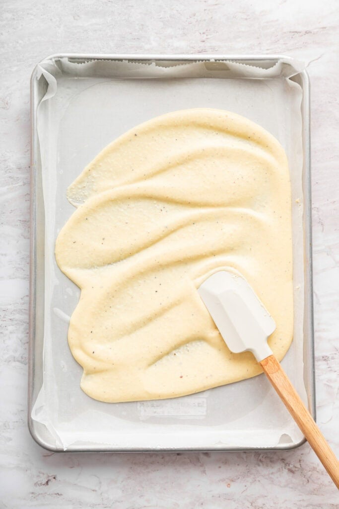 These high protein cottage cheese wraps are made with eggs and pantry seasonings—that’s it. An easy low carb alternative that tastes delish! Rubber spatula spreading batter for cottage cheese wrap.