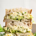 Two halves of an egg salad sandwich stacked on top of each other.