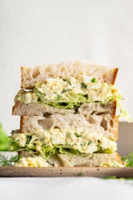 Two halves of an egg salad sandwich stacked on top of each other.