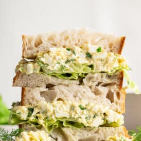 Two halves of an egg salad sandwich stacked on top of each other.