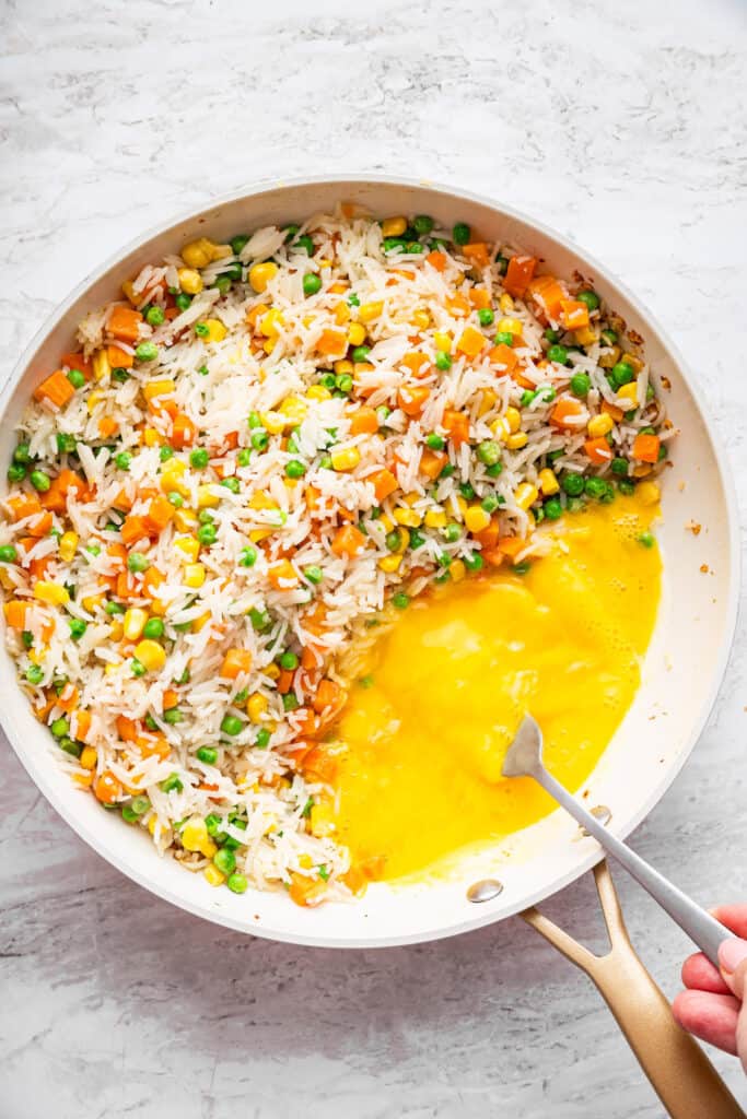 This 10-minute vegetable fried rice is the ultimate quick meal or side dish! Easy, flavorful, and perfect for busy weeknights. Cooking egg on side of pan with fried rice.