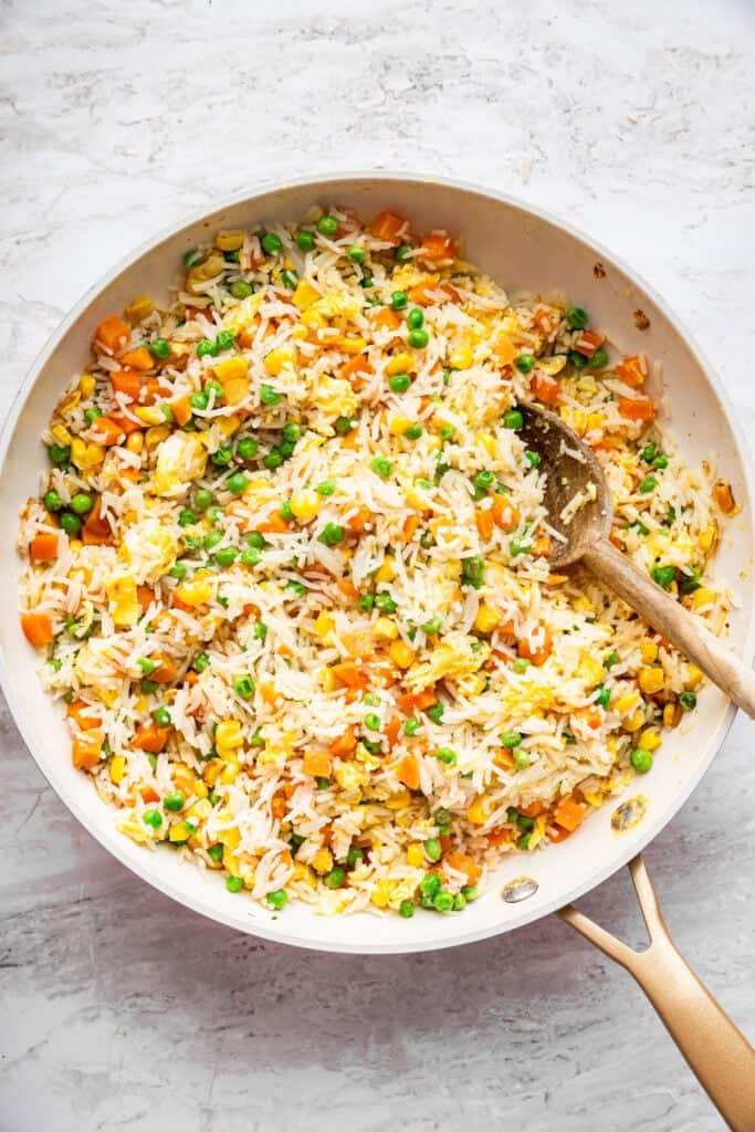 This 10-minute vegetable fried rice is the ultimate quick meal or side dish! Easy, flavorful, and perfect for busy weeknights. Stirring together vegetable fried rice in skillet.