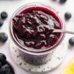 Spoonful of blueberry compote in jar.