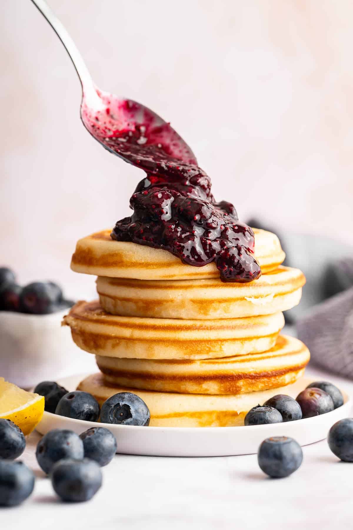 Sweet, jammy berries simmer into a quick blueberry compote that instantly upgrades pancakes, yogurt, desserts, and more. Just 3 ingredients! Spooning blueberry compote onto stack of pancakes.