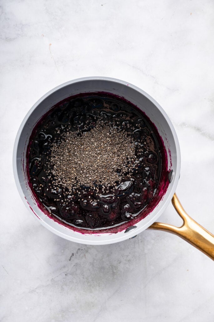 Sweet, jammy berries simmer into a quick blueberry compote that instantly upgrades pancakes, yogurt, desserts, and more. Just 3 ingredients! Chia seeds added to pan of blueberry compote.