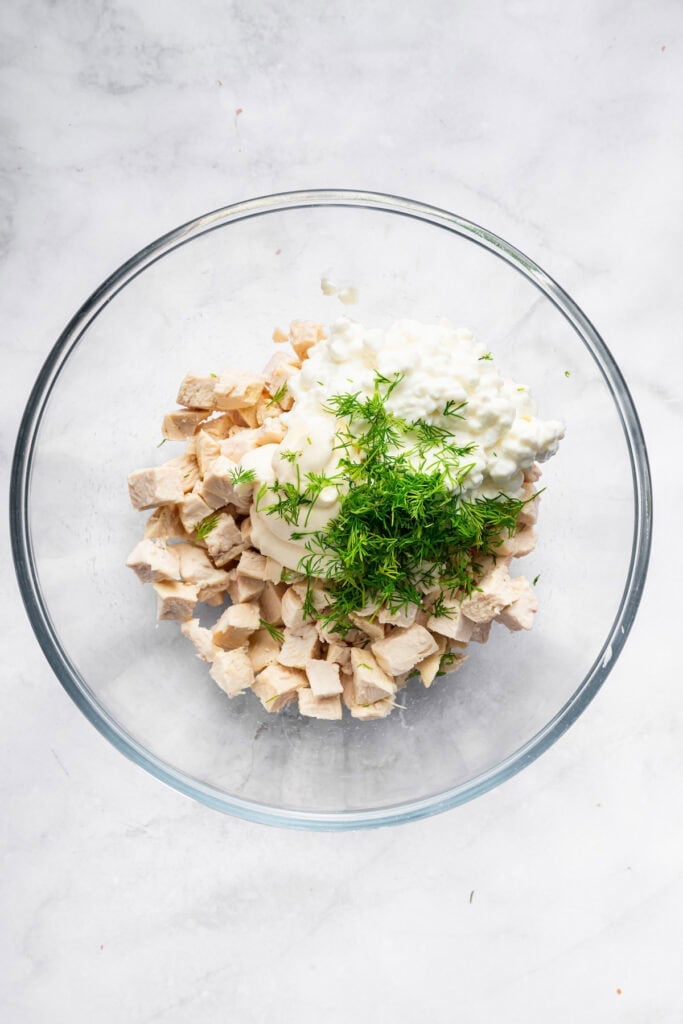 Ingredients for cottage cheese chicken salad in glass bowl.