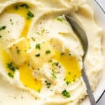 Spoon in bowl of Instant Pot mashed potatoes with butter.