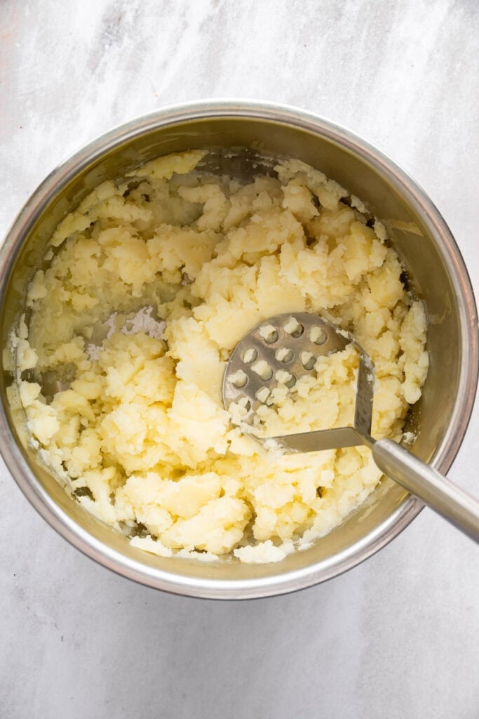 Potato masher mashing potatoes in Instant Pot.