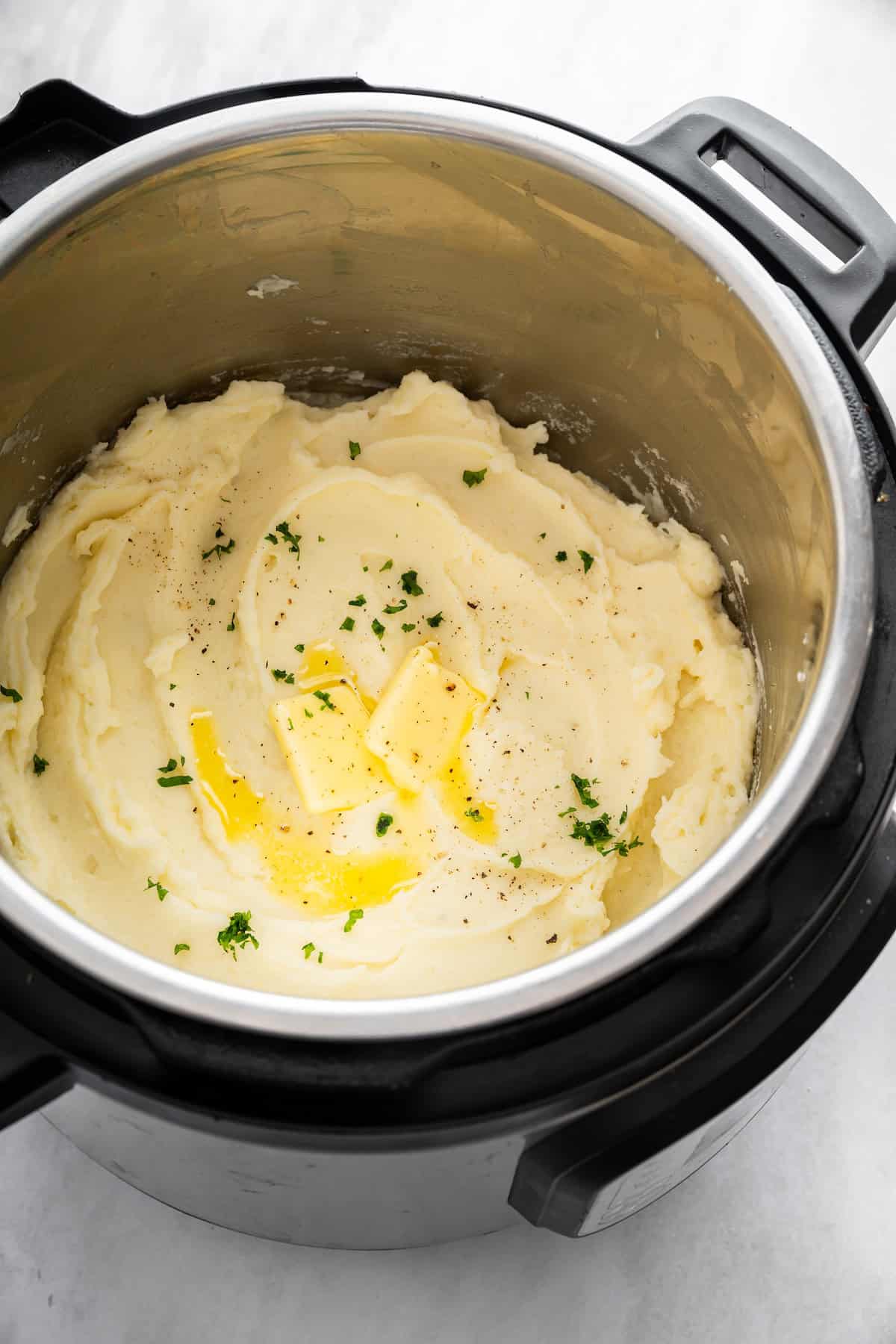 Mashed potatoes in Instant Pot with butter and herbs.