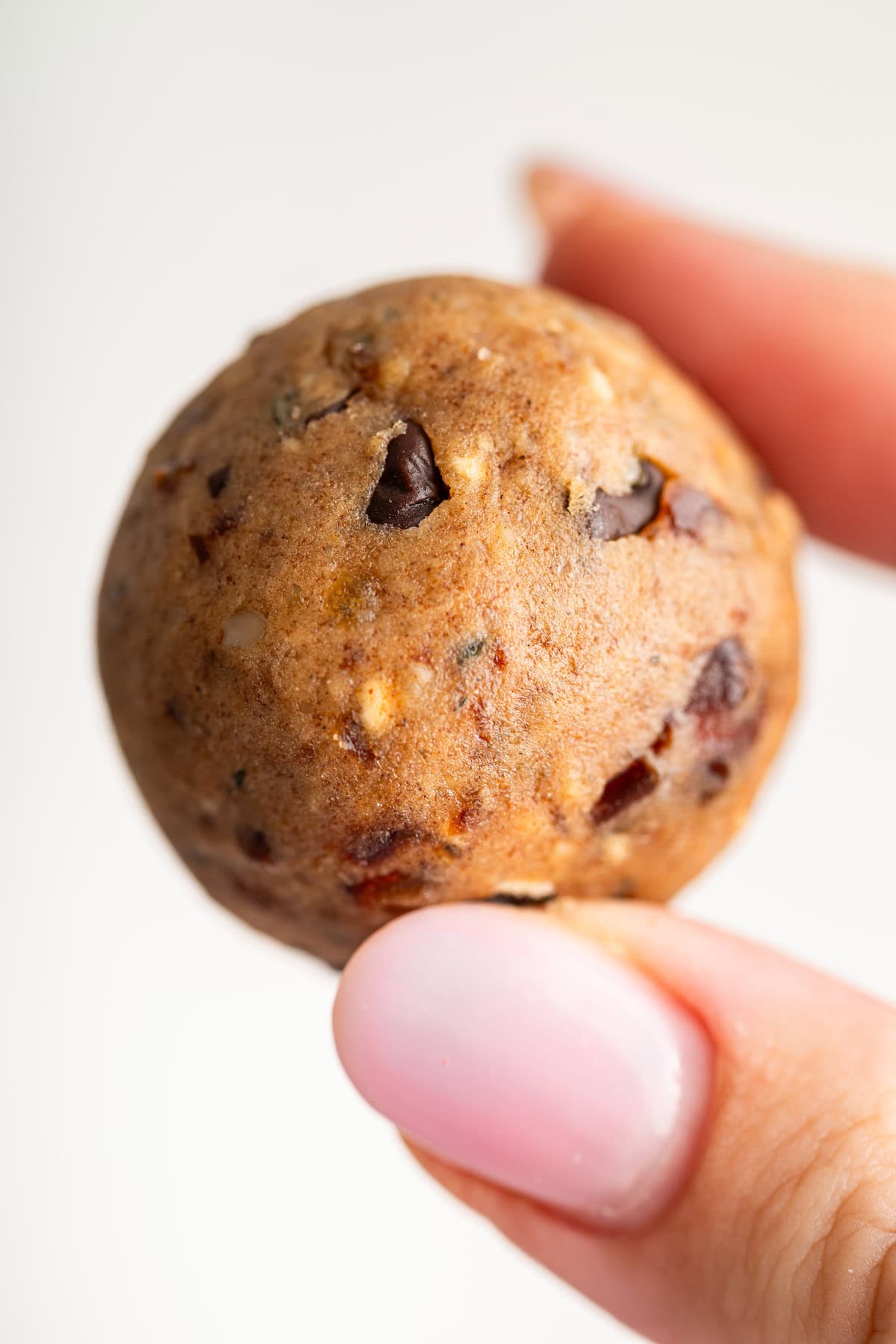 Fingers holding chocolate chip peanut butter protein ball.