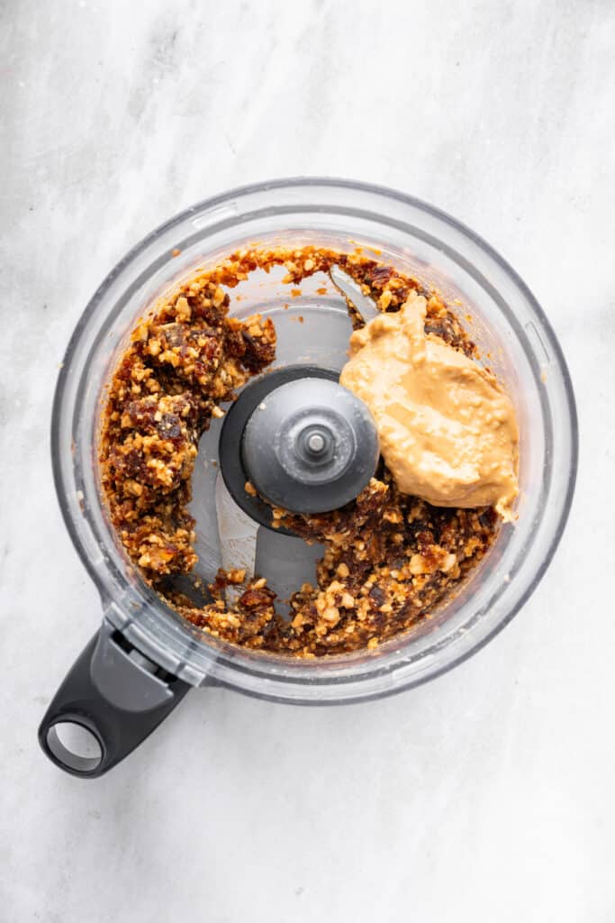 Peanut butter added to protein ball mixture in food processor.