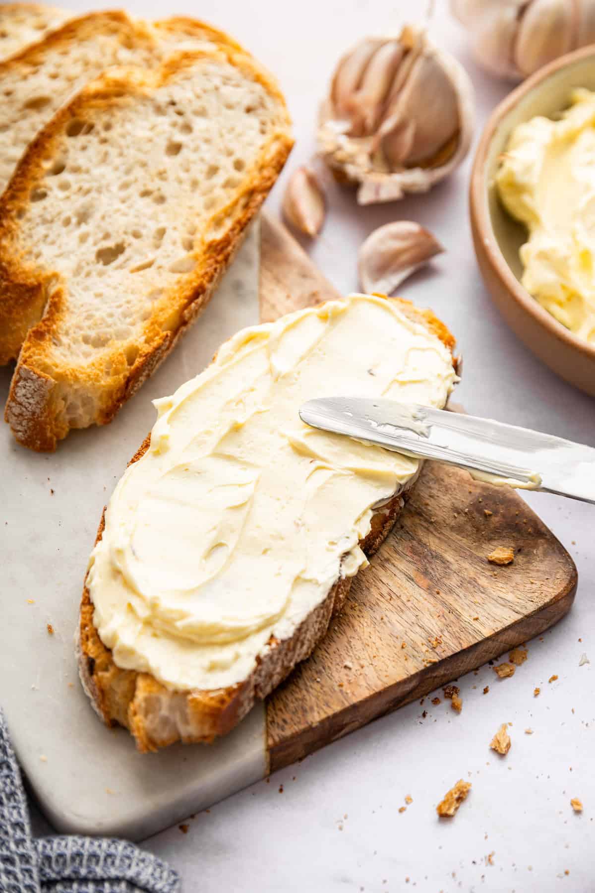 This roasted garlic butter recipe is one of the easiest ways to make just about anything taste even better. You only need 2 ingredients! Spreading garlic butter onto slice of bread.
