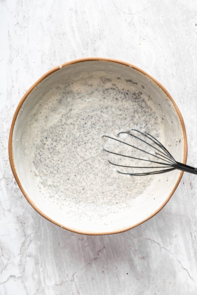 Whisking together chia seeds, coconut milk, maple syrup, and vanilla extract.