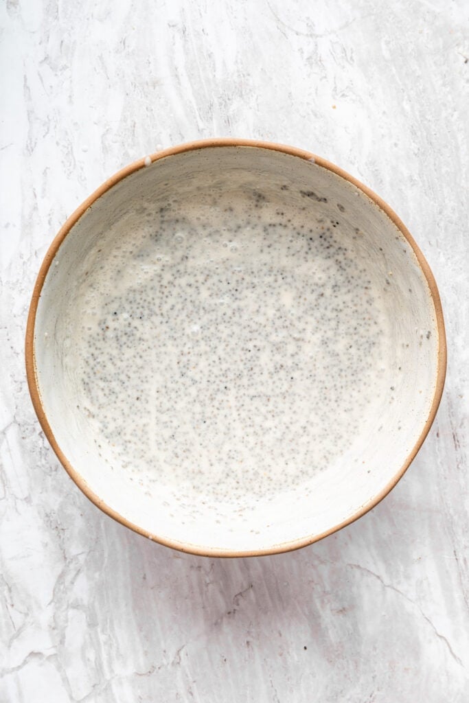 A mixture of chia seeds, coconut milk, maple syrup, and vanilla extract in a bowl.