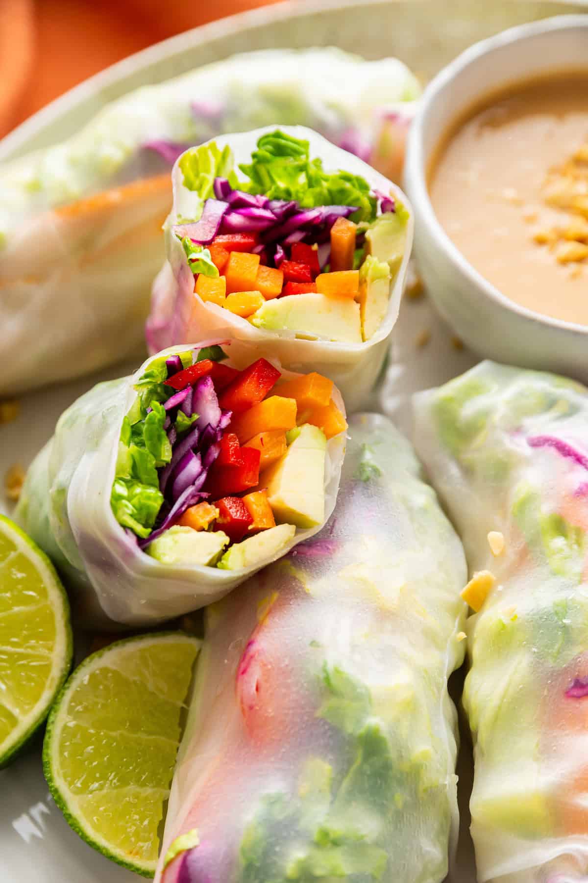 On warm days, this summer rolls recipe is a must. Crisp veggies and avocado are wrapped in rice paper for a refreshing, no-cook meal. Close-up of a summer roll cut in half to reveal the veggies inside.