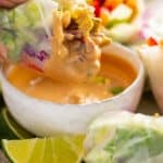 Dipping a summer roll in spicy peanut dipping sauce.