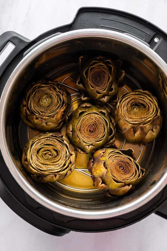 Overhead image of whole steamed artichokes in an Instant Pot.