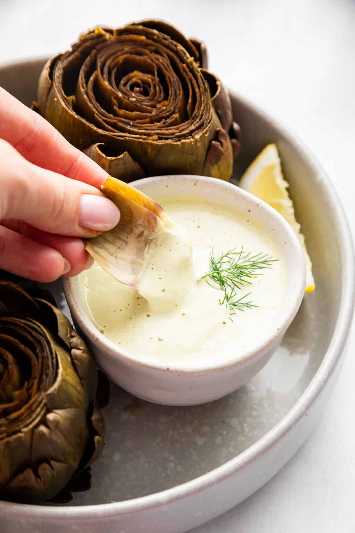 Dipping an artichoke leaf into lemon dill sauce.