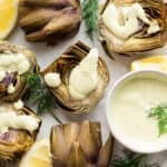 Halved steamed artichokes with lemon dill sauce.