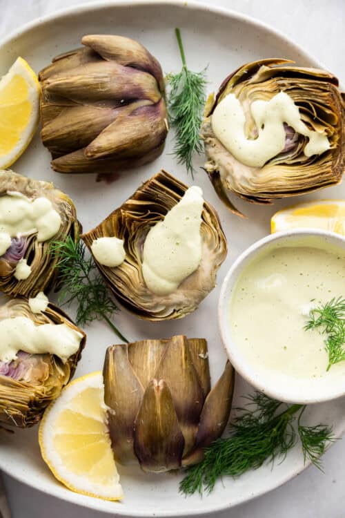 Halved steamed artichokes with lemon dill sauce.