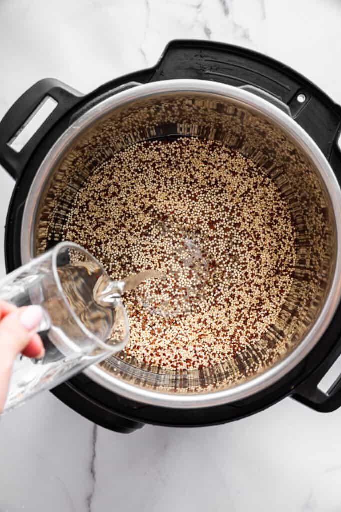 Adding water to an Instant Pot with quinoa.